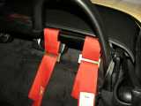 The shoulder belts just wrap around the roll bar.